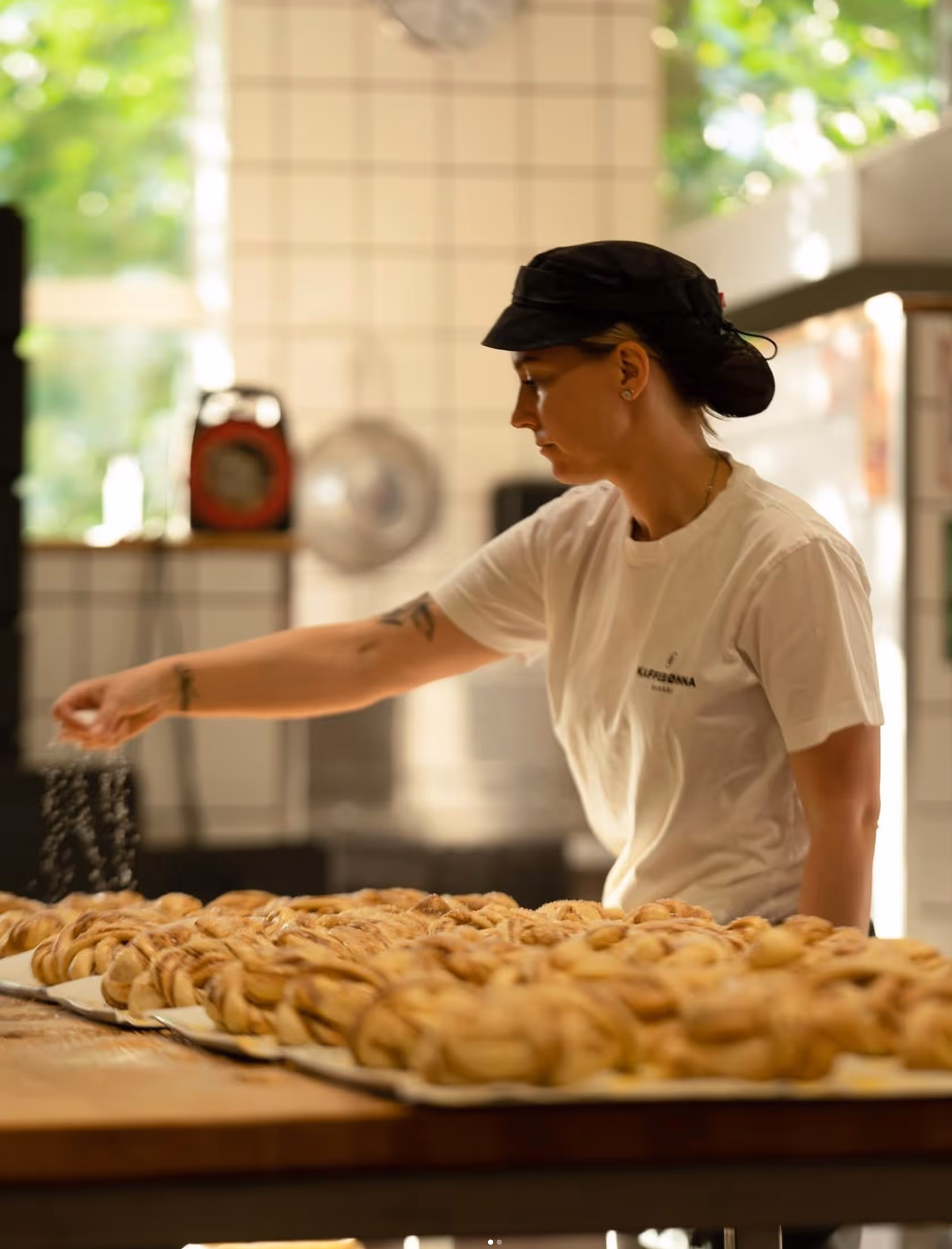 Baker strør sukker over kanelsnurrer